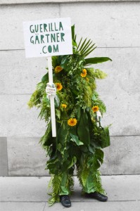 Mit Pflanzen verkleidete Person mit Schild mit Webadresse