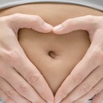 Kind oder nicht Kind? Frau hält Hand herzförmig auf ihren Bauch