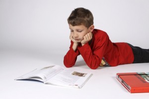 Nachhilfe Junge liegt am Bauch und liest ein Buch