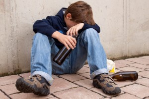 Sucht bei Jugendlichen Jugendlicher mit einer Bierflache sitzt auf der Strasse