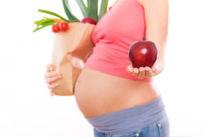 Schwangere Frau mit einem Apfel in der Hand