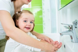 mother washing baby hands Kind am Waschbecken