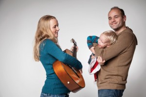 Bild: Frau spielt Gitarre Mann hält Kind am Arm