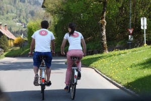 zwei Radfahrer von hinten mit Logo auf Rücken