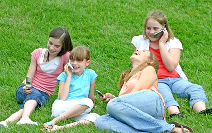 Kinder auf einer Wiese mit Handys