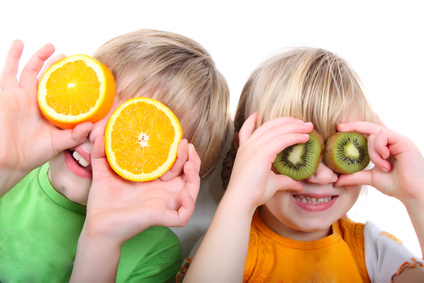 Kinder spielen mit Orangen und Kiwis